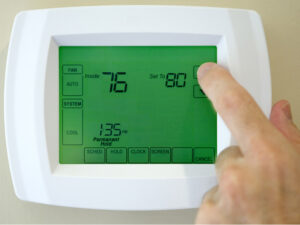 person setting temperature on thermostat